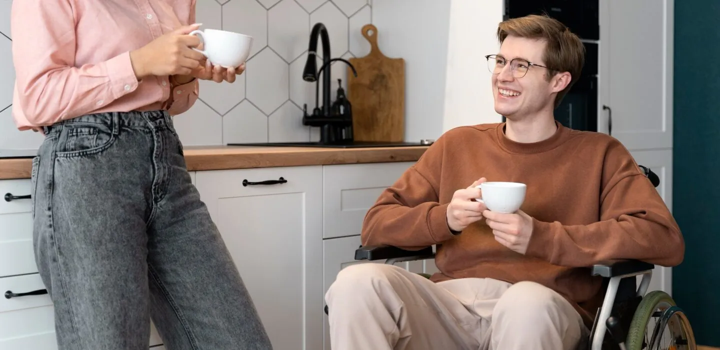 Ein Rollstuhlfahrer trinkt mit einer Freundin einen Kaffee